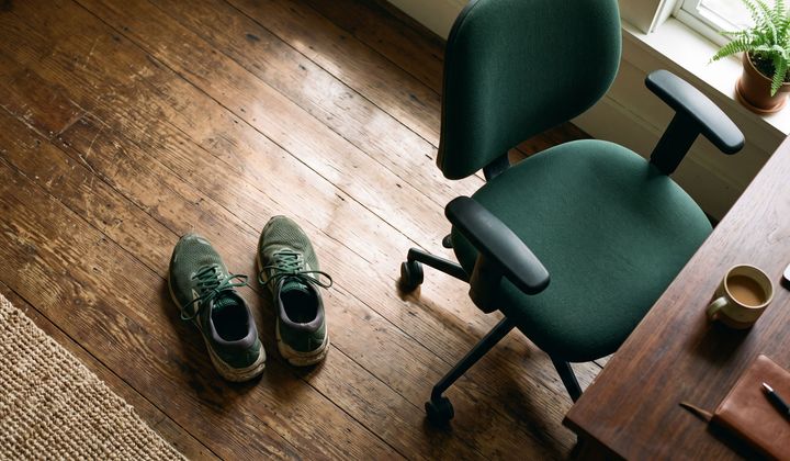 Laufschuhe auf Holzboden neben einem zurückgeschobenen Bürostuhl, Morgenlicht fällt durchs Fenster
